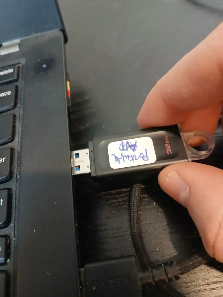 a person inserting a USB in a laptop USB port